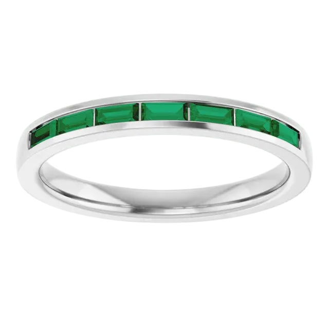 Silver ring with green gemstones on a white background